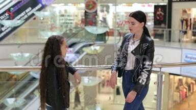 时髦的年轻女孩和妹妹在购物中心散步。